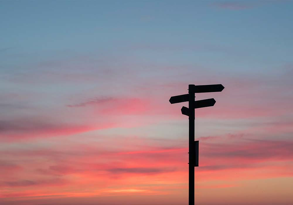 Signpost with sun setting