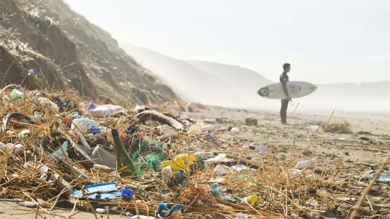Surfer looking out to sea with landfill in the foreground