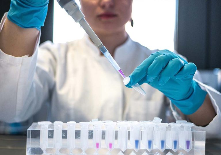 Female scientist pipetting colored chemicals into a tube