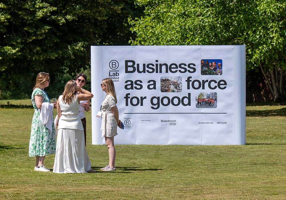 Sign saying "Business as a force for good" with 4 people speaking at B Corp event
